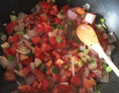 Eenpansgerecht met o.a. bosui, tomaat en rode ui.