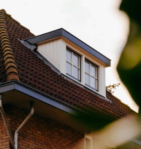 Houten dakkapel met dubbel raam op zolder.