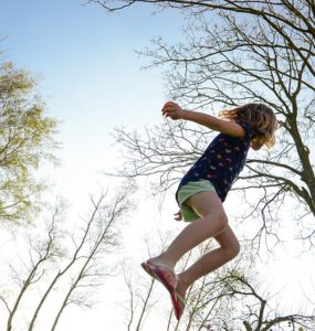 Meisje springt op een trampoline hoog in de lucht.